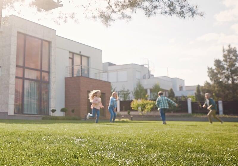 Foto von spielenden Kindern auf einer Rasenfläche eines Einfamilienhauses